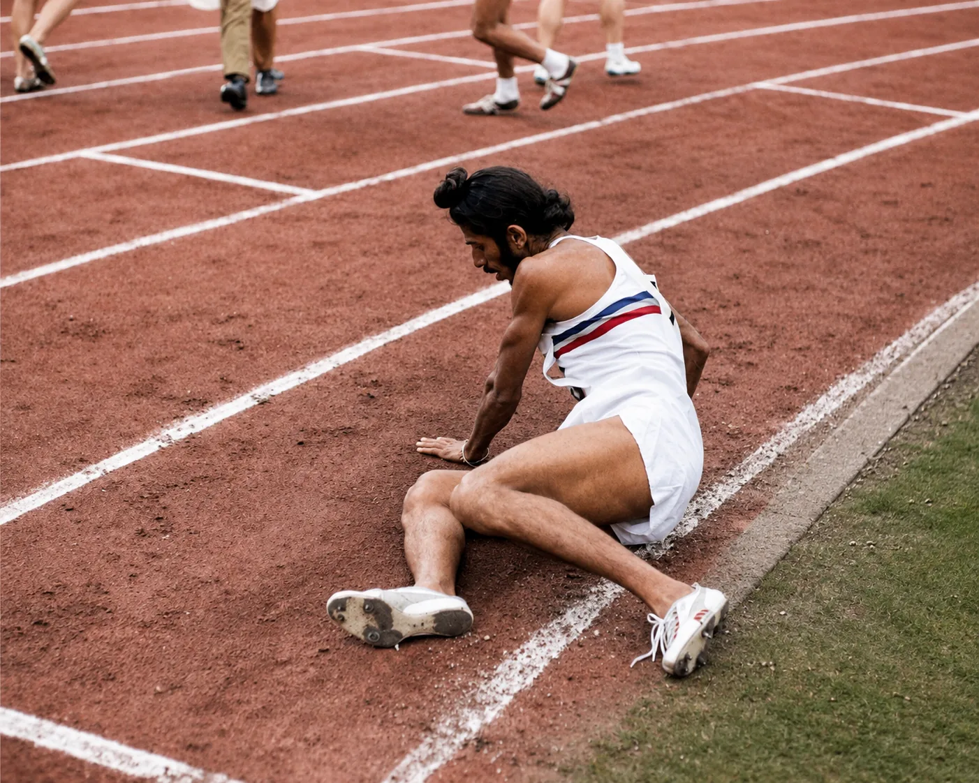 Illustration of a runner sitting collapsed on a cinder track after a race, seen from behind, as the other competitors walk away.